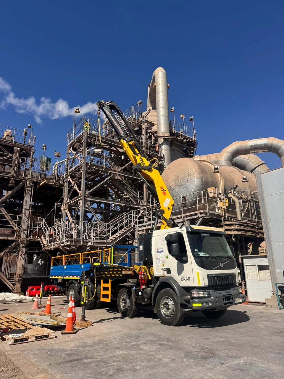 Camión pluma en estructura industrial. Apoyo de izaje junto a infraestructura de proceso.