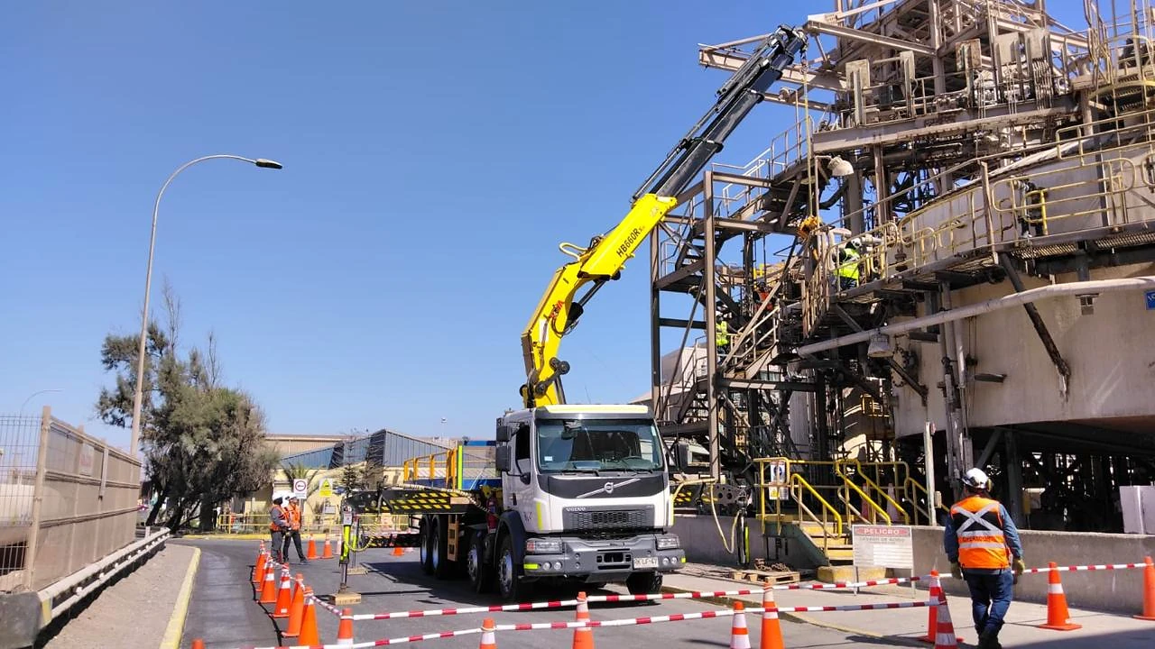 Camión pluma en instalación industrial. Operación de izaje ejecutada en planta con área segregada y control operacional.
