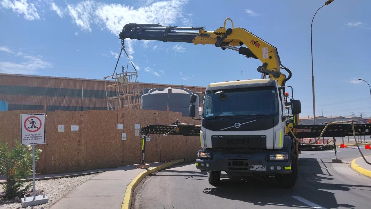 Camión pluma en patio industrial. Equipo dispuesto para maniobras de apoyo operacional y logística.