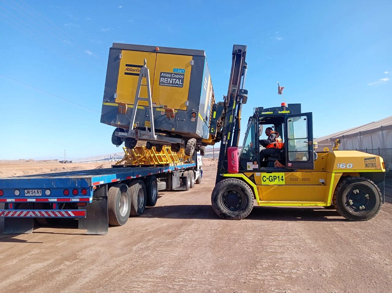 Carga de equipo sobre plataforma. Grúa horquilla apoyando la carga de un equipo industrial para su traslado.