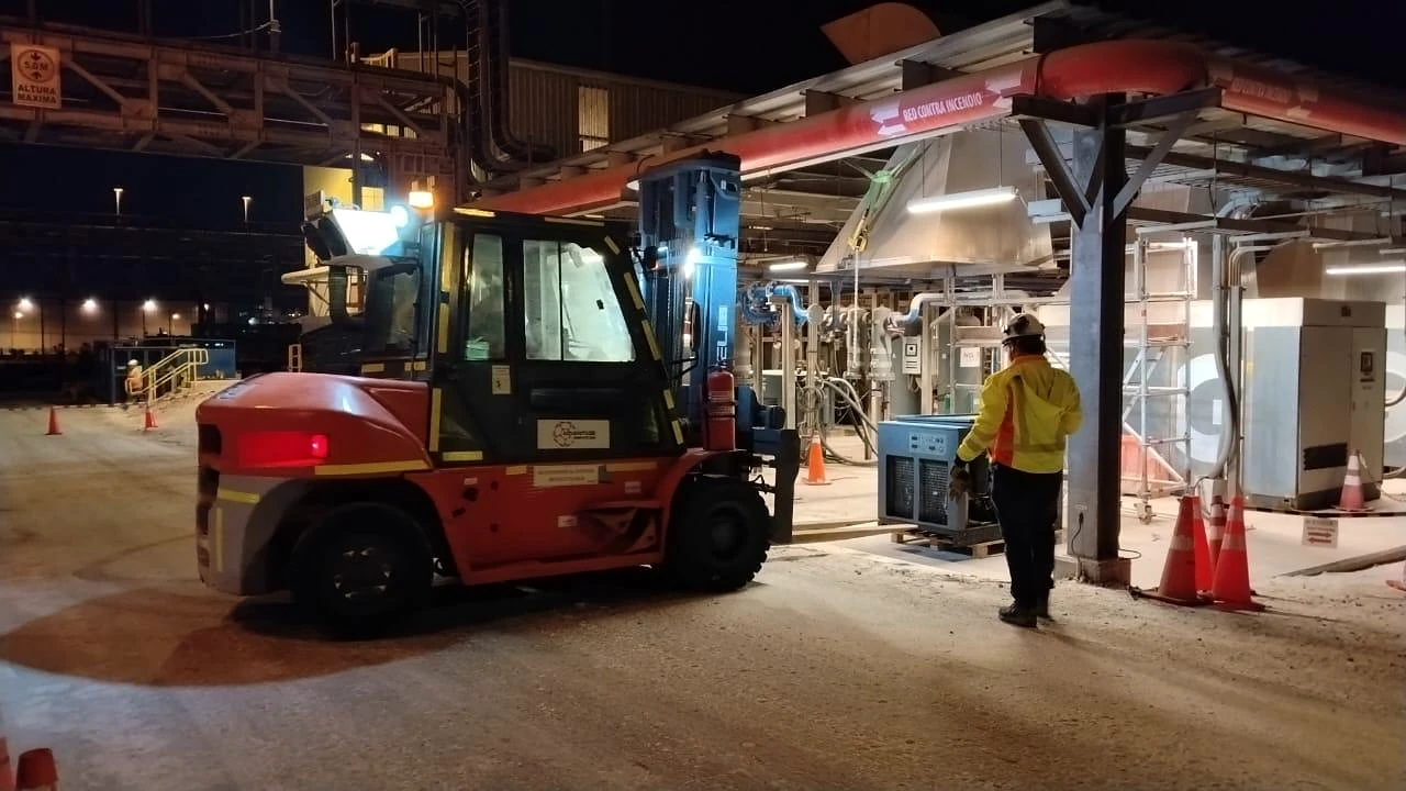 Grúa horquilla en operación nocturna. Manipulación controlada de carga en instalación industrial durante turno nocturno.