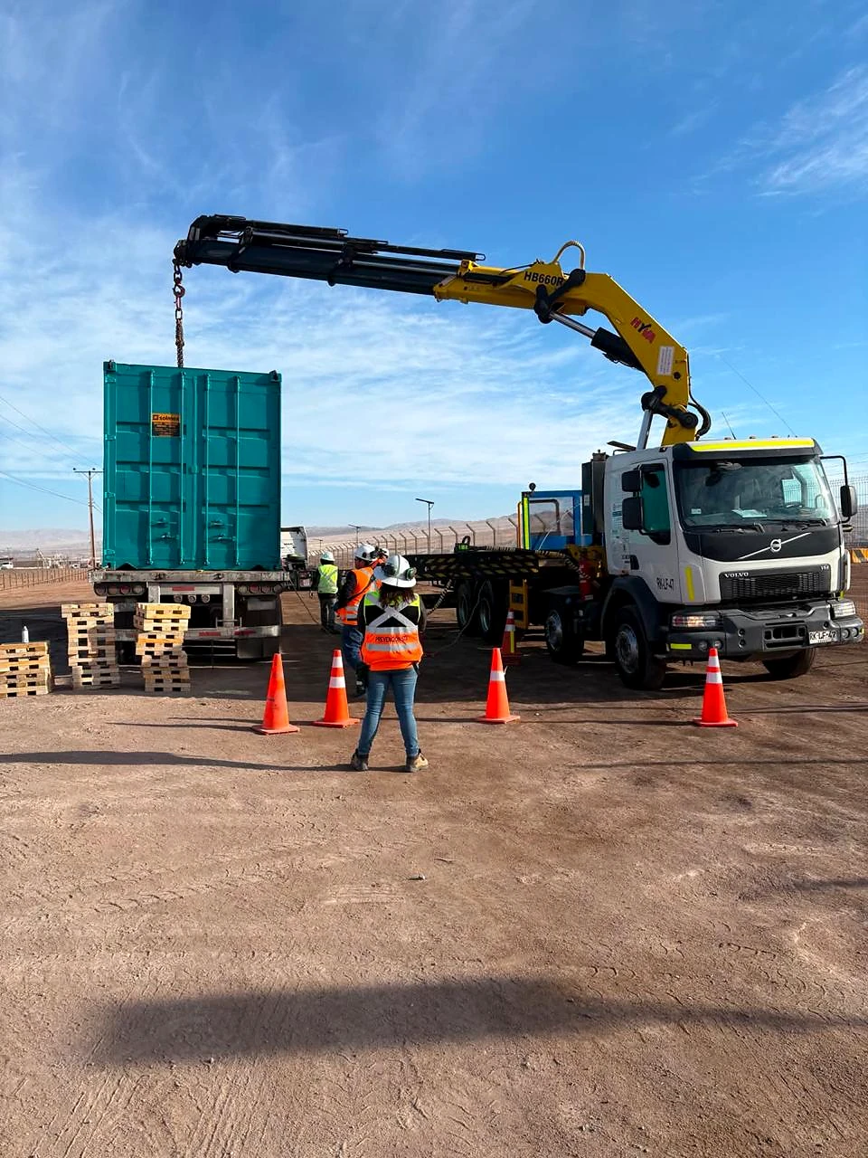 Izaje de contenedor industrial. Levantamiento de contenedor con camión pluma en patio operacional.