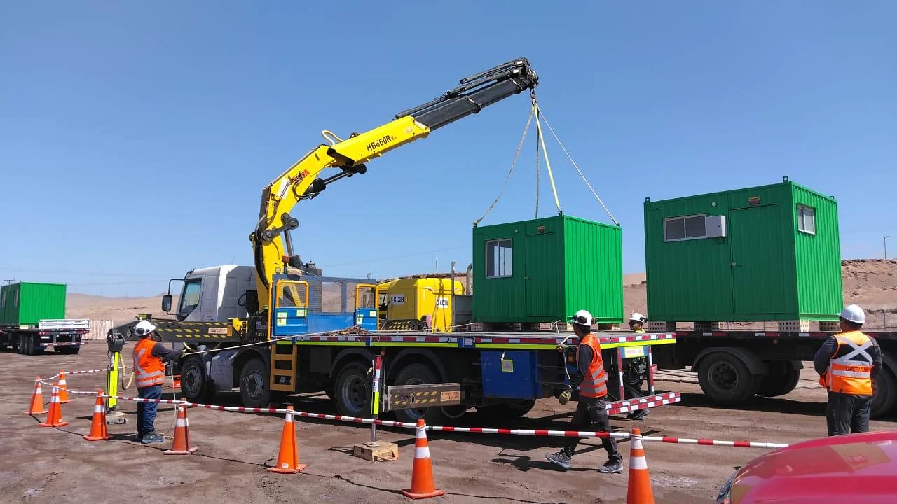 Izaje y posicionamiento de módulos. Camión pluma trabajando con módulos industriales y personal coordinado en terreno.